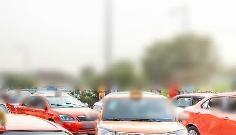 Taxis orange à l’arrêt dans une rue d’Abidjan, devant une rangée d’arbres.